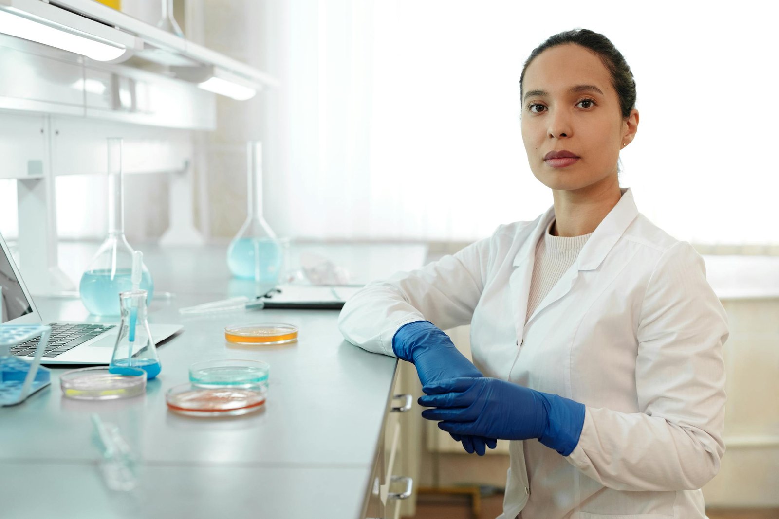 Female scientist in a lab coat conducting research with laboratory glassware.