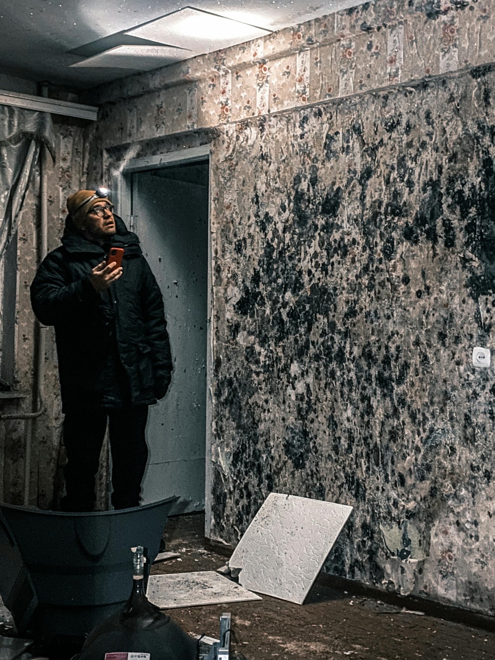 Man inspects mold-covered walls in an abandoned building